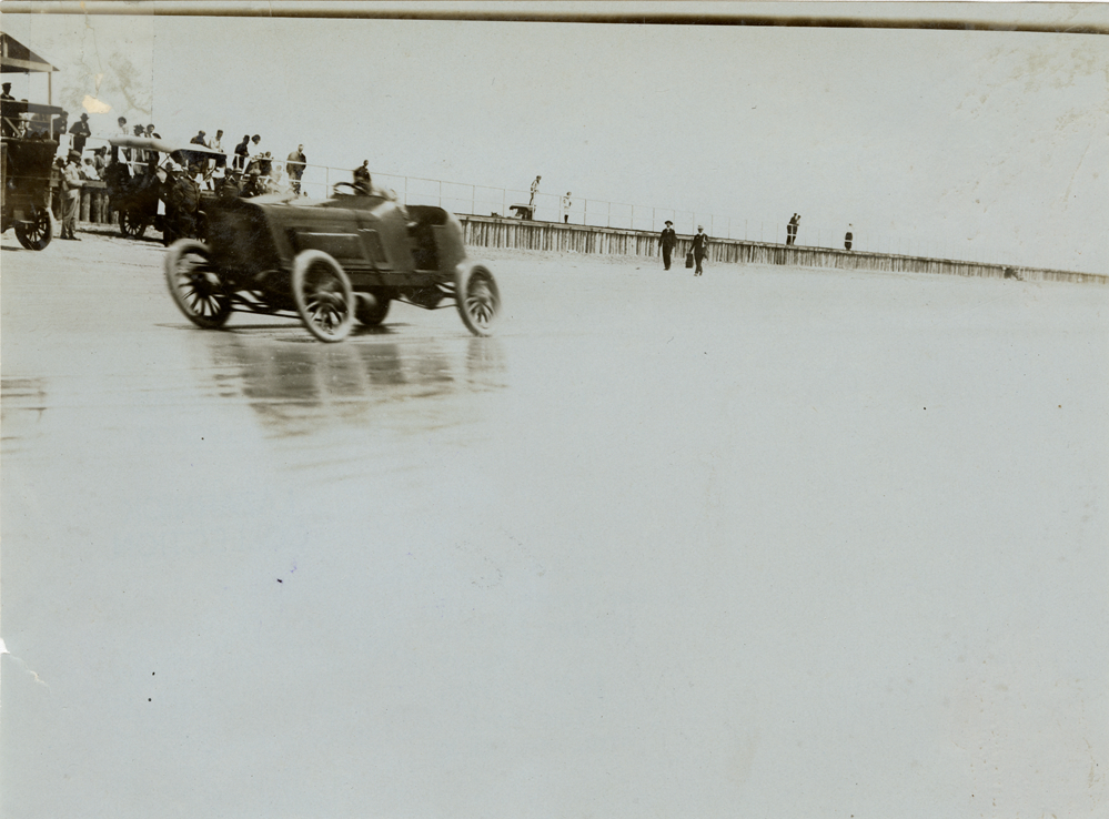 An old photo containing car, beach