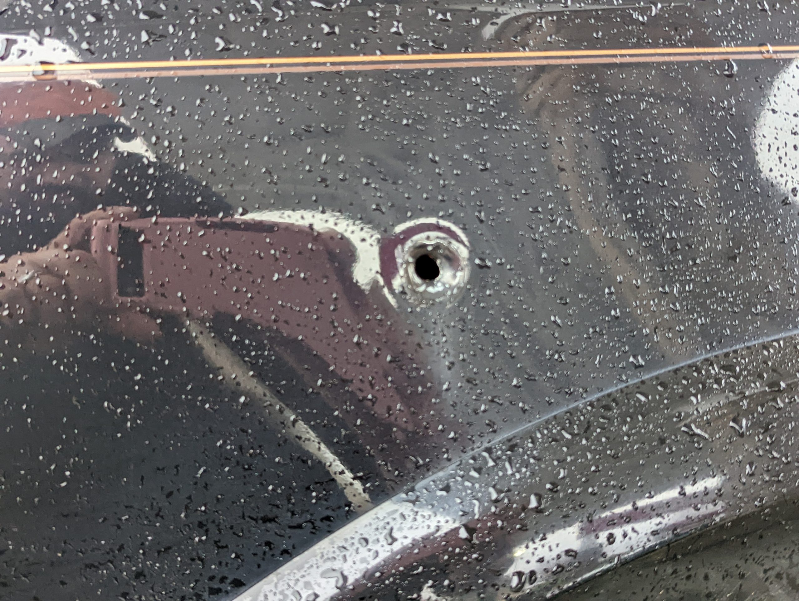 Closeup of a bullet hole in a fender.