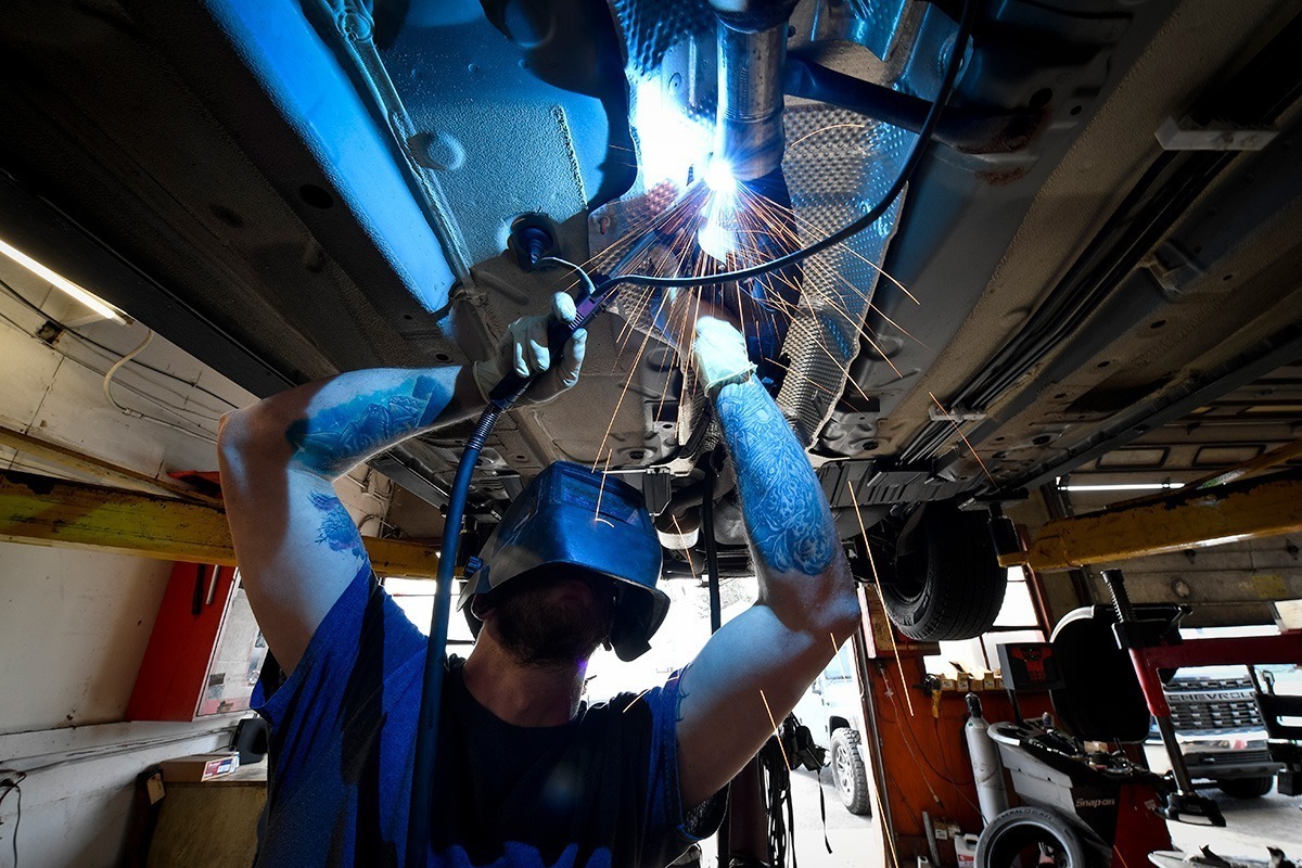 Welding exhaust under a car.