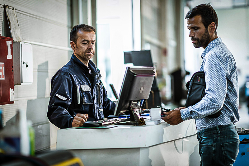 Auto counter person discussing repair details with customer.